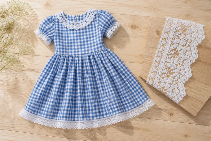 Blue gingham childrenswear with white lace trim and lace swatch